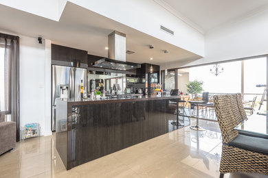 Medium sized contemporary galley kitchen/diner in Perth with an integrated sink, flat-panel cabinets, dark wood cabinets, granite worktops, glass sheet splashback, stainless steel appliances, travertine flooring and an island.