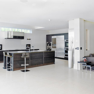 Design ideas for an expansive modern l-shaped open plan kitchen with a submerged sink, flat-panel cabinets, dark wood cabinets, stainless steel appliances, an island, grey floors and grey worktops.