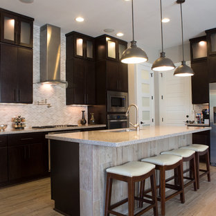 Inspiration for a large contemporary l-shaped separate kitchen in Austin with an undermount sink, flat-panel cabinets, dark wood cabinets, limestone benchtops, beige splashback, mosaic tile splashback, stainless steel appliances, light hardwood floors, with island, brown floor and beige benchtop.