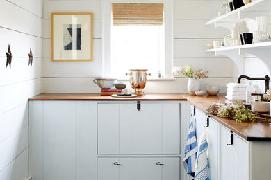 Foto de cocinas en L de estilo de casa de campo sin isla con armarios con paneles lisos, puertas de armario blancas, encimera de madera y suelo gris