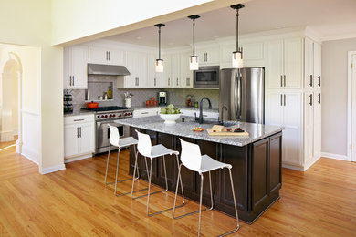 Mid-sized transitional l-shaped medium tone wood floor open concept kitchen photo in Boston with an undermount sink, recessed-panel cabinets, white cabinets, granite countertops, gray backsplash, subway tile backsplash, stainless steel appliances and an island