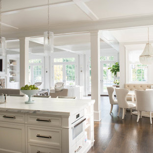 Design ideas for a large victorian galley eat-in kitchen in New York with a farmhouse sink, recessed-panel cabinets, white cabinets, marble benchtops, stainless steel appliances, dark hardwood floors and with island.