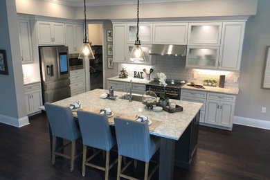 Open concept kitchen - large mediterranean l-shaped brown floor open concept kitchen idea in Tampa with a single-bowl sink, recessed-panel cabinets, white cabinets, quartz countertops, white backsplash, ceramic backsplash, stainless steel appliances and an island