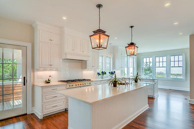 Inspiration for a large traditional galley kitchen in Philadelphia with a belfast sink, shaker cabinets, medium hardwood flooring, an island, white cabinets, white splashback and stainless steel appliances.