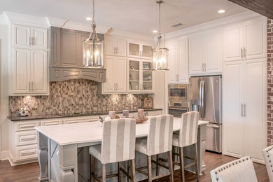 Transitional u-shaped vinyl floor and brown floor open concept kitchen photo in Other with a farmhouse sink, raised-panel cabinets, gray cabinets, quartz countertops, gray backsplash, metal backsplash, stainless steel appliances, an island and white countertops