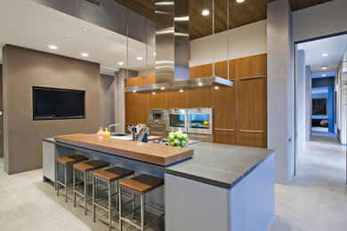 Example of a trendy galley gray floor kitchen design in Chicago with flat-panel cabinets, medium tone wood cabinets, stainless steel appliances and an island
