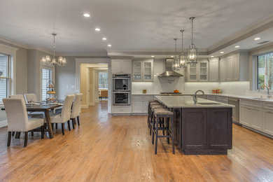 Example of a transitional medium tone wood floor kitchen design in Boston with an undermount sink, shaker cabinets, gray cabinets, quartzite countertops, white backsplash, ceramic backsplash and stainless steel appliances