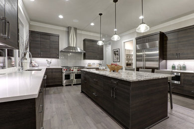 Example of a large minimalist u-shaped medium tone wood floor and gray floor enclosed kitchen design in Chicago with flat-panel cabinets, dark wood cabinets, gray backsplash, glass tile backsplash, stainless steel appliances, an island and an undermount sink