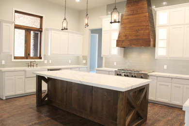 Inspiration for a huge transitional single-wall medium tone wood floor and brown floor open concept kitchen remodel in Dallas with a farmhouse sink, beaded inset cabinets, white cabinets, marble countertops, gray backsplash, subway tile backsplash, stainless steel appliances, an island and white countertops