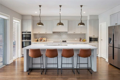 Inspiration for a large transitional galley medium tone wood floor kitchen pantry remodel in Sydney with an undermount sink, shaker cabinets, gray cabinets, quartz countertops, gray backsplash, subway tile backsplash, stainless steel appliances, an island and multicolored countertops