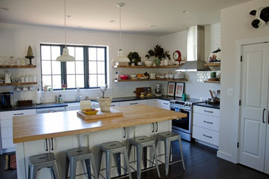 Example of a large country l-shaped dark wood floor eat-in kitchen design in DC Metro with a farmhouse sink, shaker cabinets, white cabinets, solid surface countertops, white backsplash, ceramic backsplash, stainless steel appliances and an island