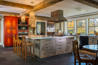 Large country l-shaped kitchen/diner in Portland Maine with a belfast sink, shaker cabinets, distressed cabinets, stainless steel appliances, an island, grey floors and grey worktops.
