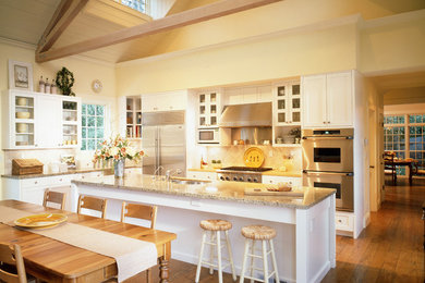 Geräumige Landhausstil Wohnküche in L-Form mit Glasfronten, weißen Schränken, Granit-Arbeitsplatte, Küchengeräten aus Edelstahl, braunem Holzboden, Kücheninsel, Doppelwaschbecken und Küchenrückwand in Weiß in San Francisco