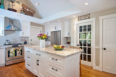 Inspiration for a large transitional u-shaped light wood floor eat-in kitchen remodel in Portland Maine with an undermount sink, recessed-panel cabinets, white cabinets, granite countertops, gray backsplash, subway tile backsplash, stainless steel appliances and an island