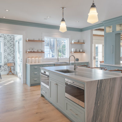 Eat-in kitchen - large country u-shaped light wood floor and beige floor eat-in kitchen idea in New York with a farmhouse sink, blue cabinets, marble countertops, white backsplash, marble backsplash, stainless steel appliances, an island, gray countertops and shaker cabinets