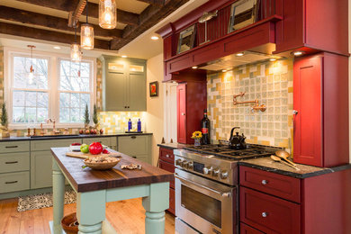 This is an example of a large rural kitchen in Boston with shaker cabinets, multi-coloured splashback, glass tiled splashback, medium hardwood flooring, an island, red cabinets, wood worktops and stainless steel appliances.
