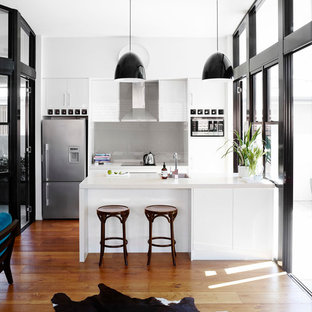 Modelo de cocina de galera, tradicional renovada, con fregadero bajoencimera, armarios con paneles lisos, puertas de armario blancas, salpicadero verde, salpicadero de vidrio templado y electrodomésticos de acero inoxidable