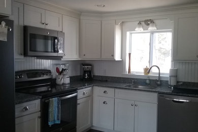 Example of a transitional dark wood floor kitchen design in Boston with a single-bowl sink, recessed-panel cabinets, white cabinets, granite countertops, white backsplash, wood backsplash and stainless steel appliances