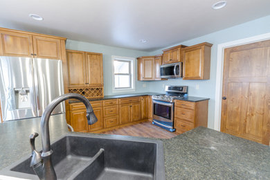 Large farmhouse l-shaped laminate floor and brown floor kitchen pantry photo in Milwaukee with a double-bowl sink, recessed-panel cabinets, medium tone wood cabinets, laminate countertops, stainless steel appliances and an island