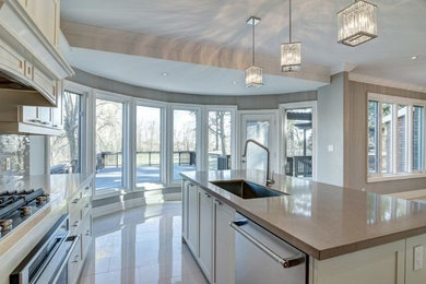 Mid-sized transitional l-shaped white floor open concept kitchen photo in Toronto with an undermount sink, shaker cabinets, white cabinets, quartz countertops, brown backsplash, stainless steel appliances, an island, gray countertops and glass tile backsplash