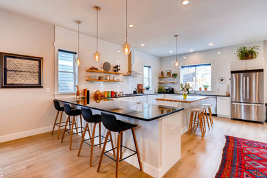 Light wood floor and gray floor kitchen photo in Denver with a double-bowl sink, shaker cabinets, white cabinets, granite countertops, white backsplash, subway tile backsplash, stainless steel appliances and an island