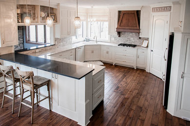 Design ideas for a classic u-shaped kitchen in Minneapolis with a built-in sink, raised-panel cabinets, white cabinets, engineered stone countertops, grey splashback, stone tiled splashback, integrated appliances, medium hardwood flooring and a breakfast bar.