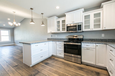 Example of a mid-sized transitional l-shaped medium tone wood floor and brown floor open concept kitchen design in Cedar Rapids with an undermount sink, recessed-panel cabinets, white cabinets, granite countertops and stainless steel appliances