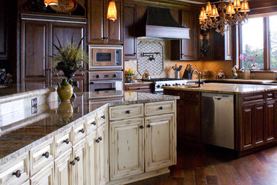 Eat-in kitchen - large traditional l-shaped dark wood floor eat-in kitchen idea in Charlotte with raised-panel cabinets, dark wood cabinets, granite countertops, beige backsplash, stone tile backsplash, paneled appliances, two islands and a farmhouse sink