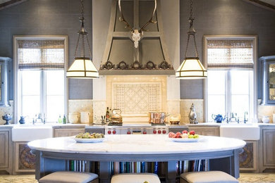 Eat-in kitchen - large mediterranean eat-in kitchen idea in Houston with a farmhouse sink, raised-panel cabinets, gray cabinets, marble countertops, beige backsplash, stone tile backsplash, stainless steel appliances and an island