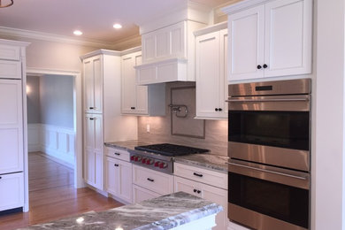 Inspiration for a mid-sized timeless medium tone wood floor and brown floor enclosed kitchen remodel in Boston with recessed-panel cabinets, white cabinets, granite countertops, gray backsplash and stainless steel appliances