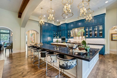 Large trendy l-shaped medium tone wood floor and brown floor eat-in kitchen photo in Dallas with a farmhouse sink, recessed-panel cabinets, blue cabinets, white backsplash, stainless steel appliances, two islands and ceramic backsplash
