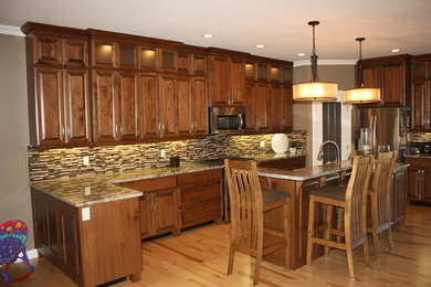 Klassisk inredning av ett avskilt, stort l-kök, med luckor med upphöjd panel, skåp i mörkt trä, granitbänkskiva, flerfärgad stänkskydd, stänkskydd i stickkakel, rostfria vitvaror, ljust trägolv och en köksö