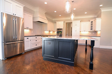 Inspiration for a medium sized traditional l-shaped kitchen/diner in Atlanta with a belfast sink, shaker cabinets, white cabinets, granite worktops, stainless steel appliances, dark hardwood flooring, an island, brown floors and black worktops.