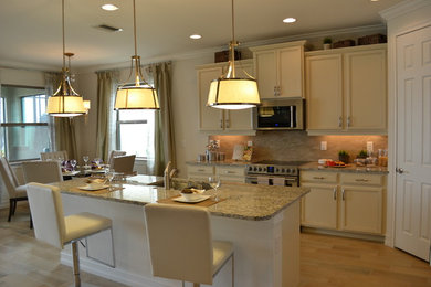 Inspiration for a mid-sized contemporary l-shaped cement tile floor eat-in kitchen remodel in Tampa with a drop-in sink, raised-panel cabinets, white cabinets, granite countertops, beige backsplash, stone tile backsplash, stainless steel appliances and an island