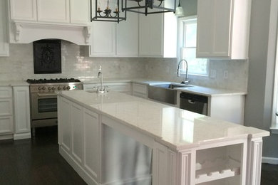 Example of a mid-sized transitional u-shaped dark wood floor eat-in kitchen design in Atlanta with a farmhouse sink, recessed-panel cabinets, white cabinets, an island and white backsplash