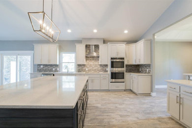 Enclosed kitchen - mid-sized traditional single-wall medium tone wood floor and brown floor enclosed kitchen idea in DC Metro with an undermount sink, shaker cabinets, white cabinets, multicolored backsplash, matchstick tile backsplash, stainless steel appliances, an island and white countertops