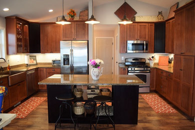 Foto de cocina de estilo americano con fregadero sobremueble, armarios estilo shaker, puertas de armario de madera oscura, encimera de cuarcita, electrodomésticos de acero inoxidable, suelo vinílico y una isla