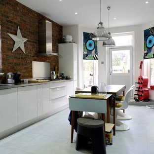 Design ideas for a medium sized eclectic galley kitchen in London with flat-panel cabinets, stainless steel worktops, an island and grey floors.
