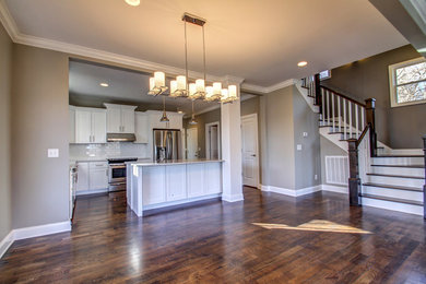 Example of a mid-sized trendy l-shaped dark wood floor eat-in kitchen design in Nashville with an undermount sink, recessed-panel cabinets, white cabinets, granite countertops, white backsplash, ceramic backsplash, stainless steel appliances and an island