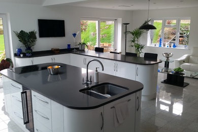 Photo of a large modern open plan kitchen in Other with an integrated sink, flat-panel cabinets, white cabinets, quartz worktops, stainless steel appliances, travertine flooring and an island.