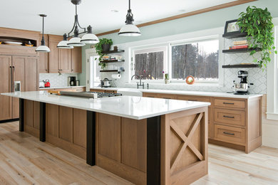 Example of a large cottage l-shaped medium tone wood floor and brown floor kitchen pantry design in Boston with a farmhouse sink, shaker cabinets, brown cabinets, quartz countertops, white backsplash, porcelain backsplash, paneled appliances, an island and white countertops