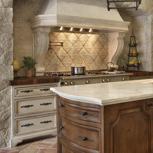 Mediterrane Küche mit Rückwand aus Terrakottafliesen, Arbeitsplatte aus Holz, Schrankfronten mit vertiefter Füllung, dunklen Holzschränken, Küchenrückwand in Beige und Mauersteinen in San Diego