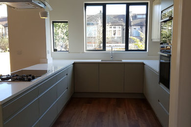 Photo of a medium sized contemporary u-shaped kitchen/diner in London with a single-bowl sink, glass-front cabinets, grey cabinets, quartz worktops, vinyl flooring, an island and white worktops.