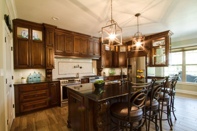 Example of a large classic u-shaped medium tone wood floor and brown floor open concept kitchen design in New Orleans with an undermount sink, shaker cabinets, medium tone wood cabinets, quartzite countertops, white backsplash, subway tile backsplash, black appliances and an island