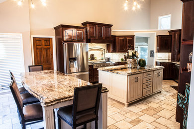Mid-sized elegant u-shaped limestone floor and beige floor open concept kitchen photo in Wichita with an undermount sink, raised-panel cabinets, distressed cabinets, granite countertops, white backsplash, ceramic backsplash, stainless steel appliances and two islands