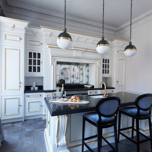 Inspiration for a medium sized traditional galley kitchen in Sussex with a submerged sink, metallic splashback, mirror splashback, an island, black floors, black worktops, recessed-panel cabinets, white cabinets, integrated appliances and dark hardwood flooring.