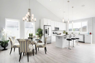 Design ideas for an expansive traditional single-wall kitchen/diner in Calgary with shaker cabinets, white cabinets, composite countertops, grey splashback, matchstick tiled splashback, stainless steel appliances, light hardwood flooring and an island.