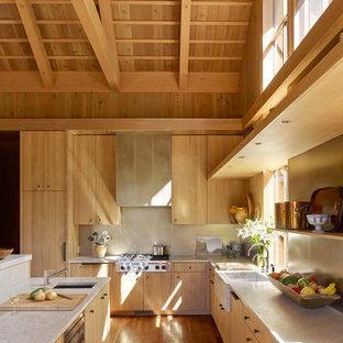 Inspiration for a country l-shaped kitchen in Portland with flat-panel cabinets, light wood cabinets, quartzite benchtops, medium hardwood floors, with island, beige benchtop, a farmhouse sink, beige splashback and stainless steel appliances.