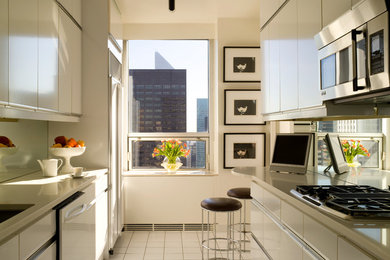 Small contemporary galley kitchen/diner in New York with a submerged sink, flat-panel cabinets, beige cabinets, mirror splashback, stainless steel appliances and no island.
