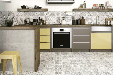 Inspiration for a mid-sized contemporary cement tile floor and multicolored floor kitchen remodel in New York with a drop-in sink, flat-panel cabinets, wood countertops, multicolored backsplash, cement tile backsplash, stainless steel appliances and a peninsula